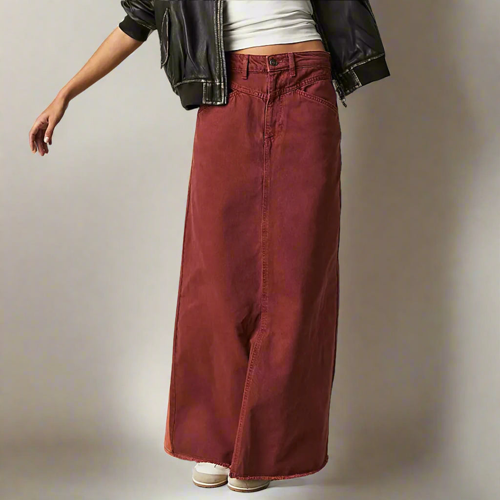 Women rust red denim maxi skirt with a straight fit and raw hem displayed from the front