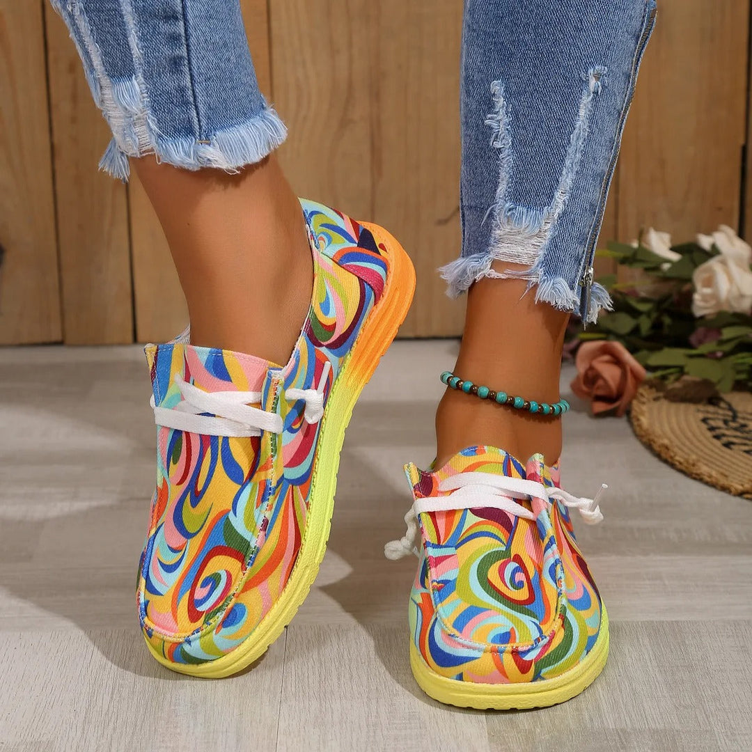 Women's multicolored printed sneakers with white laces, shown on a model's feet with distressed jeans.