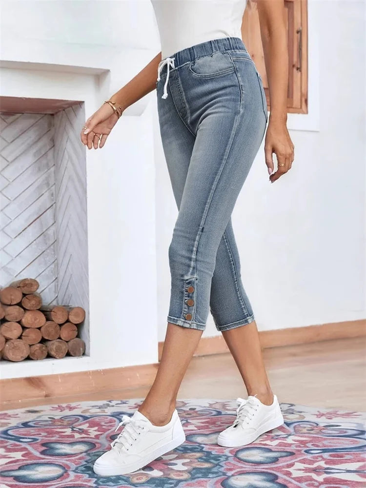Women light blue capri jeans with drawstring waist, button cuffs, and front pockets, walking pose