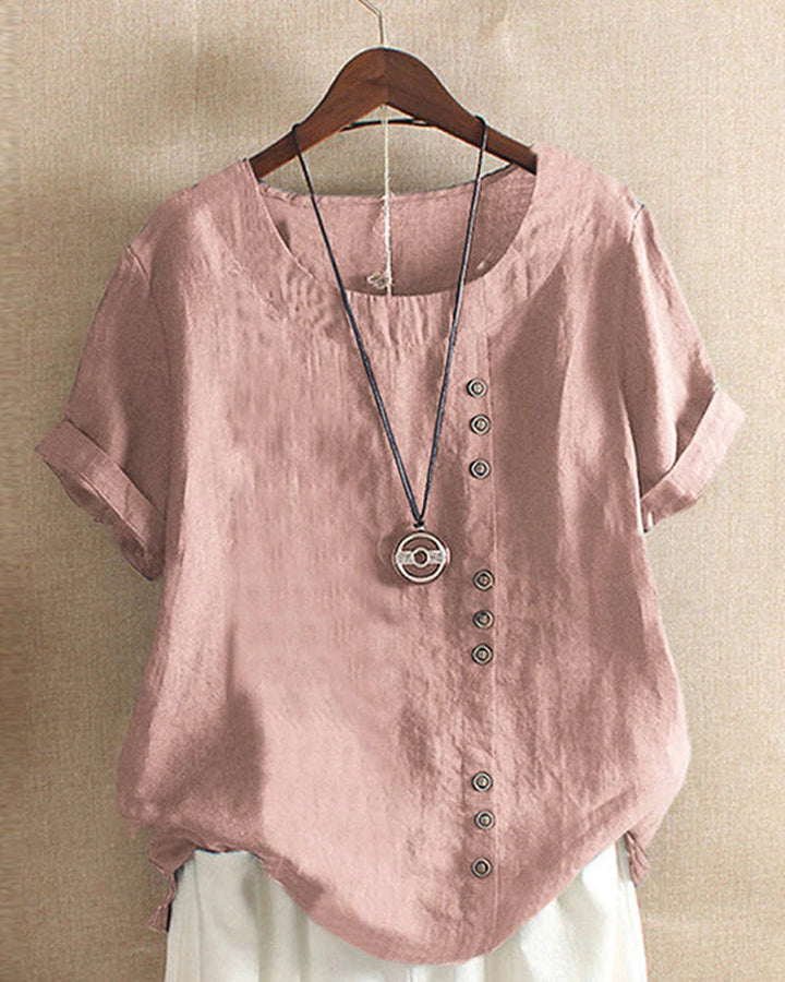 Women pink short sleeve blouse with round neck and side button placket on hanger