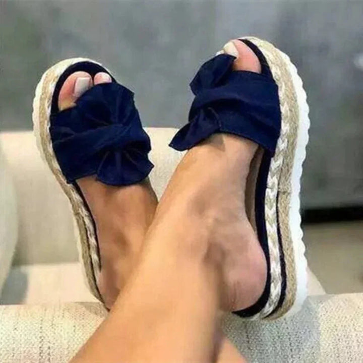Women navy bow accent platform slide sandals with woven sole, front view on feet