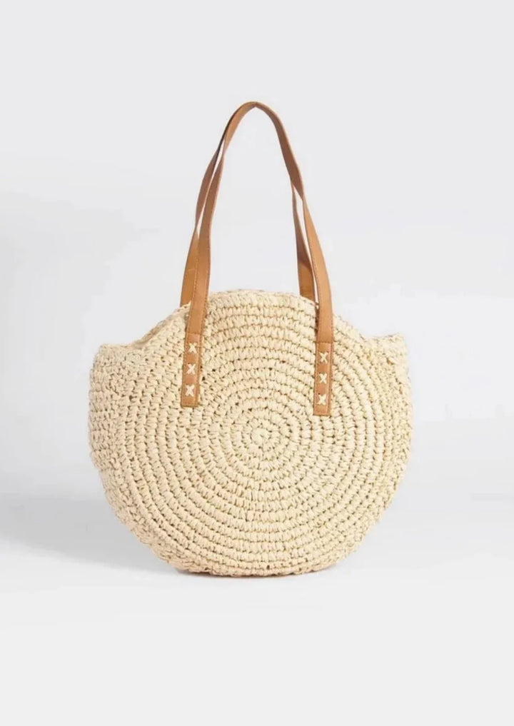 Women woven straw round tote bag with tan faux leather straps, front view