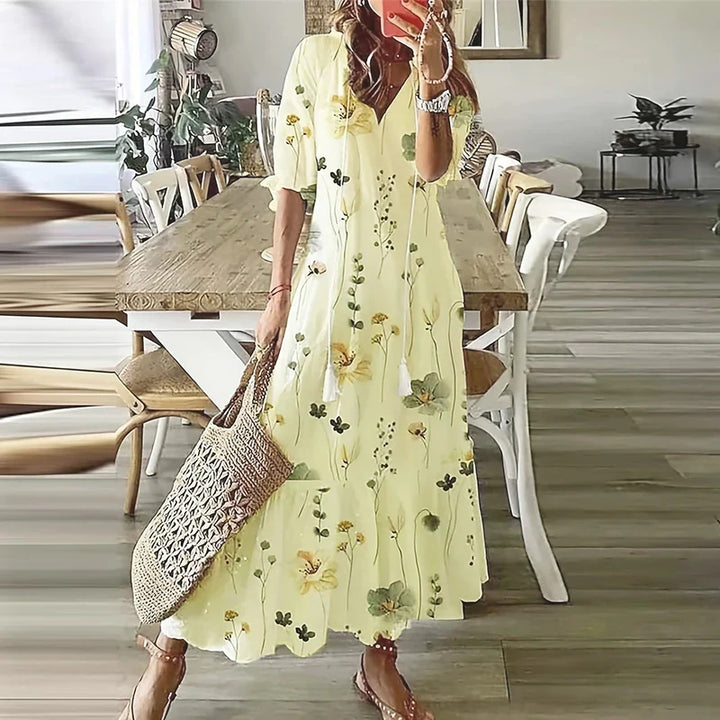 Women's yellow floral print maxi dress with V-neckline and short sleeves, casual pose