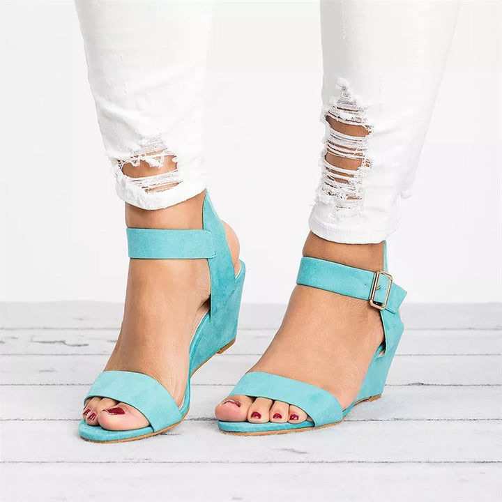 Women blue open toe wedge sandals featuring an ankle strap with buckle on a model standing.