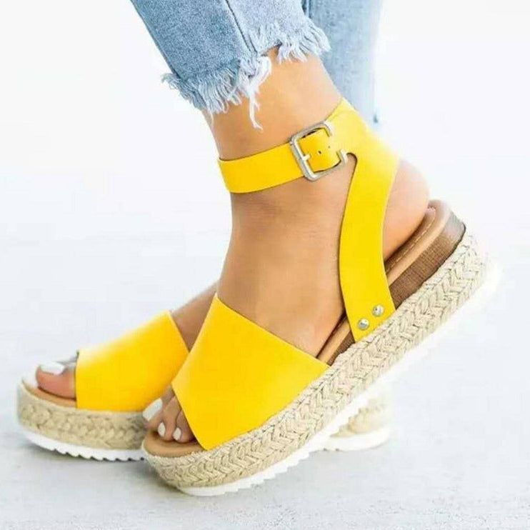 Women yellow buckle ankle strap flatform sandals with woven sole, shown with denim.