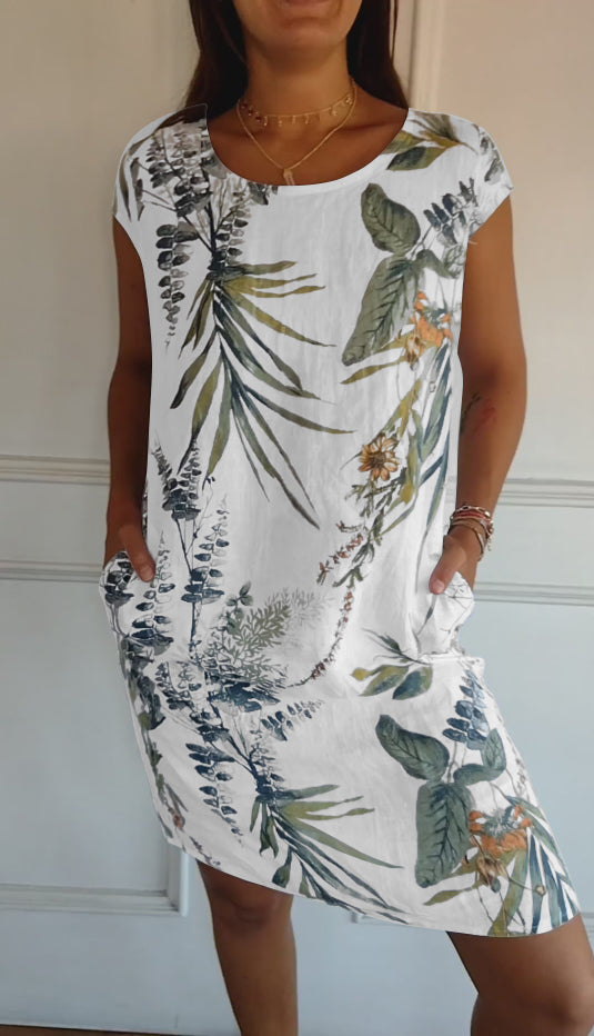 Women's white leaf print midi dress with short sleeves and scoop neck, front view with hands in pockets