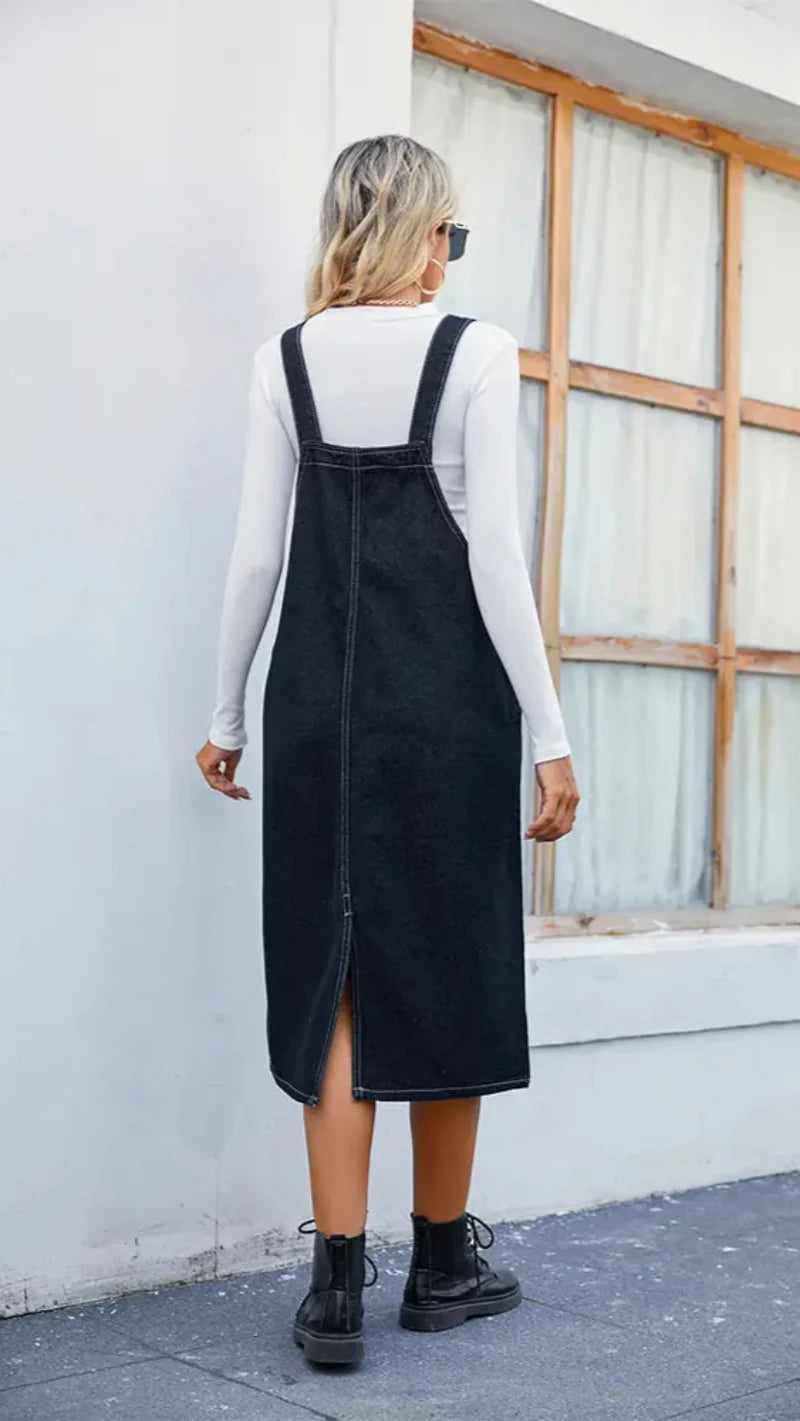 Women dark blue denim pinafore midi dress, back view showing shoulder straps and center seam