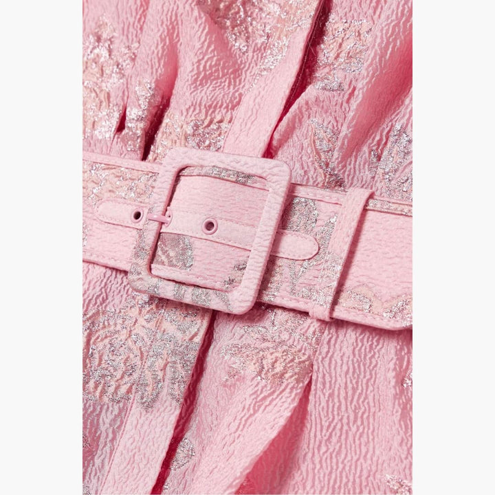 Close-up of pink floral dress fabric with embossed texture and matching belt buckle