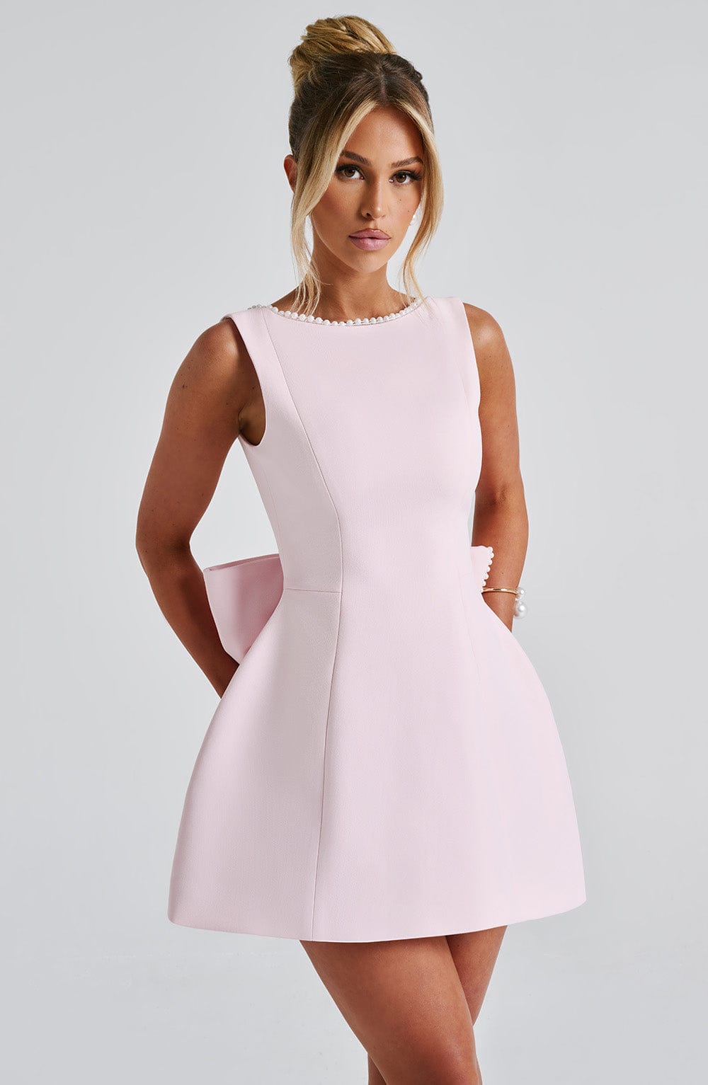 Women light pink mini dress showing side view of pearl neckline and back bow