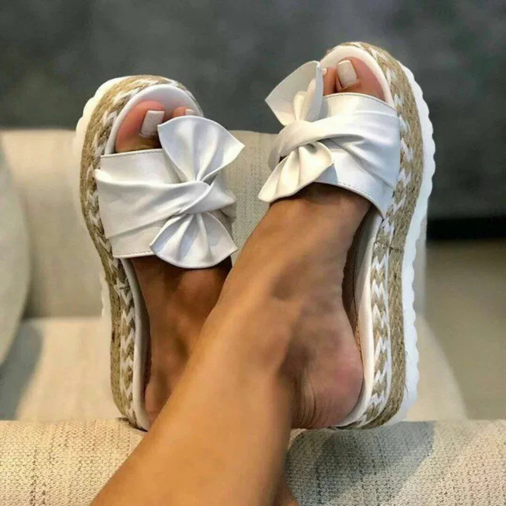Women white bow accent platform slide sandals with patterned sole, overhead view on feet
