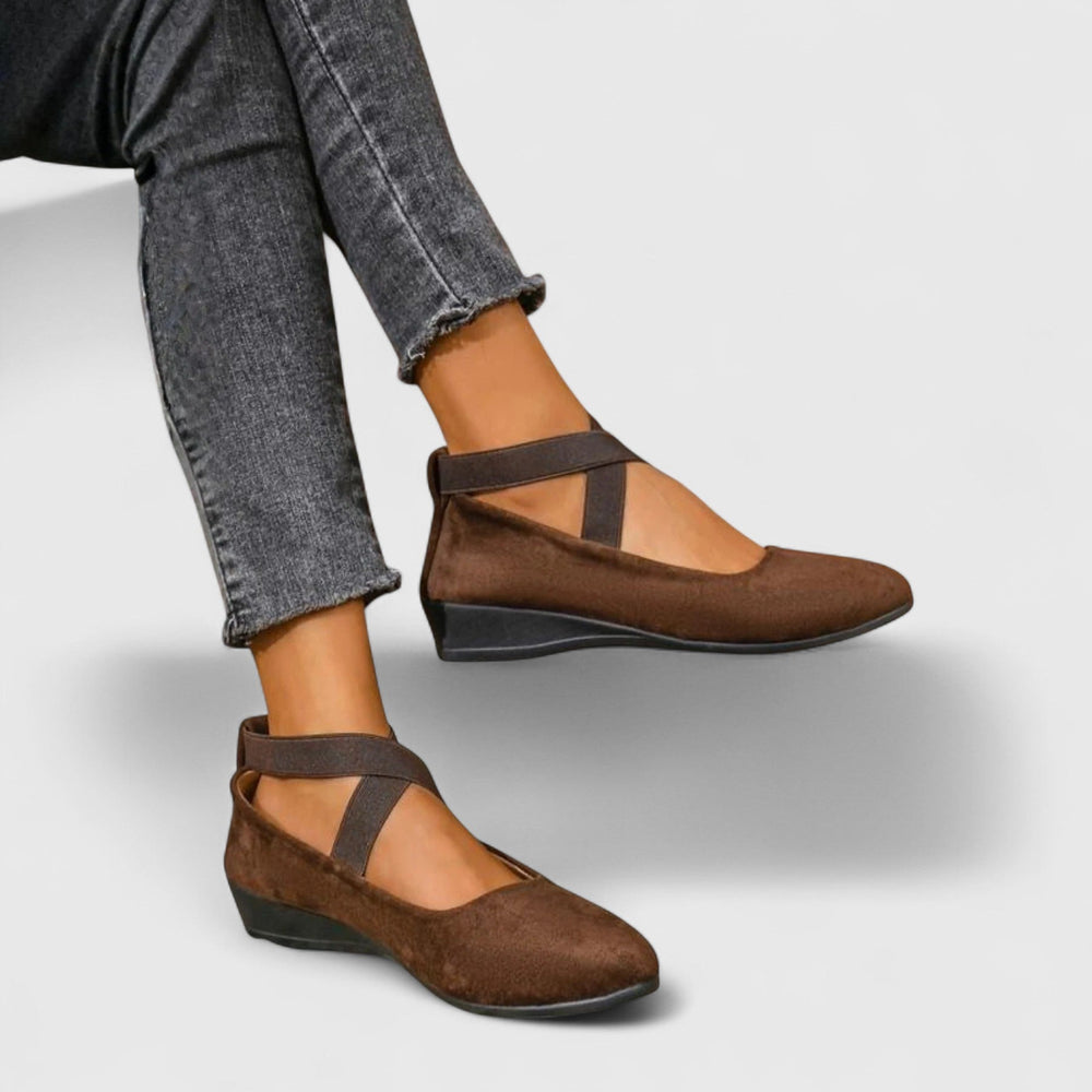 Women brown strappy round toe wedge flats worn with dark wash jeans, showcasing the crisscross straps.