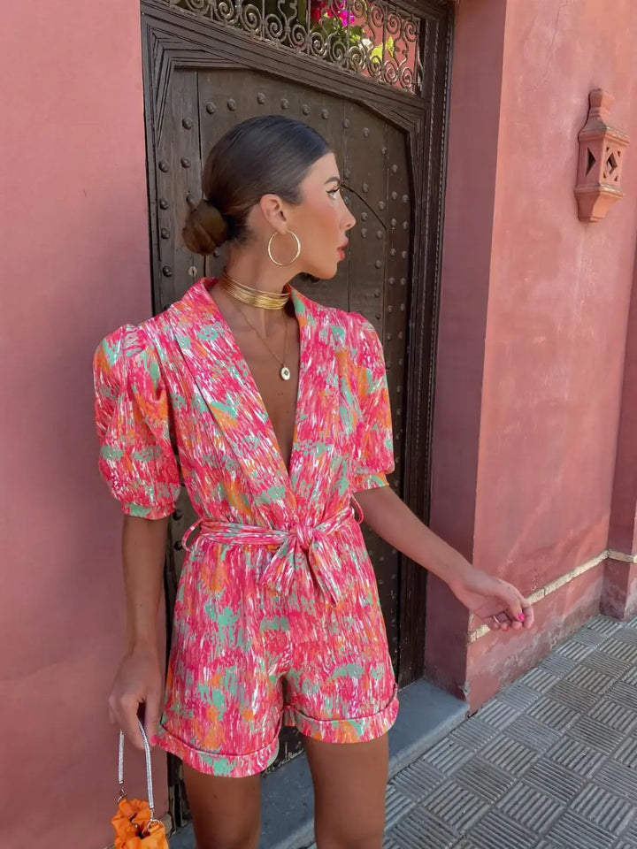 Women's pink geometric metallic printed short sleeve romper, looking to the side, three quarter view.