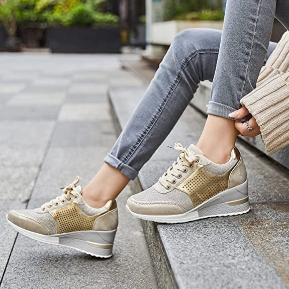 Women's champagne gold wedge sneakers with perforated sides and white sole on steps
