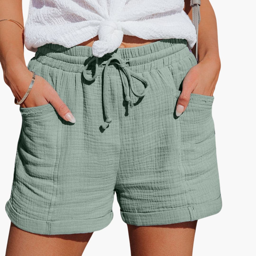 Women light green shorts with elastic drawstring waist and front pockets, worn with white top.
