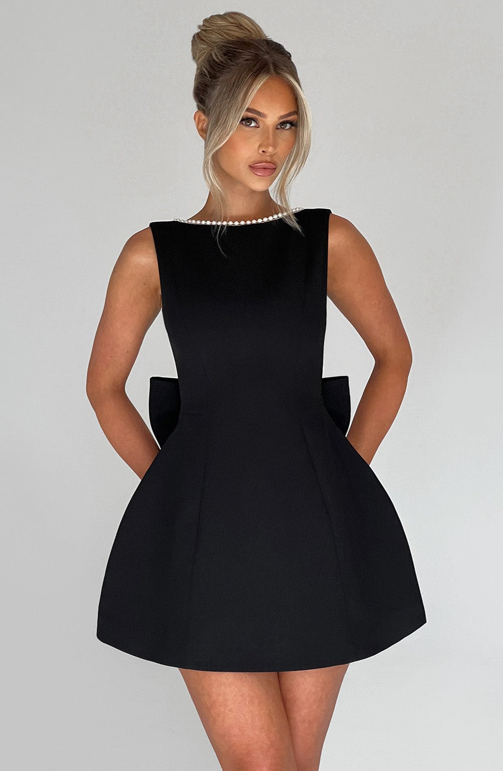 Women black mini dress with pearl-trimmed boat neckline and structured back bow