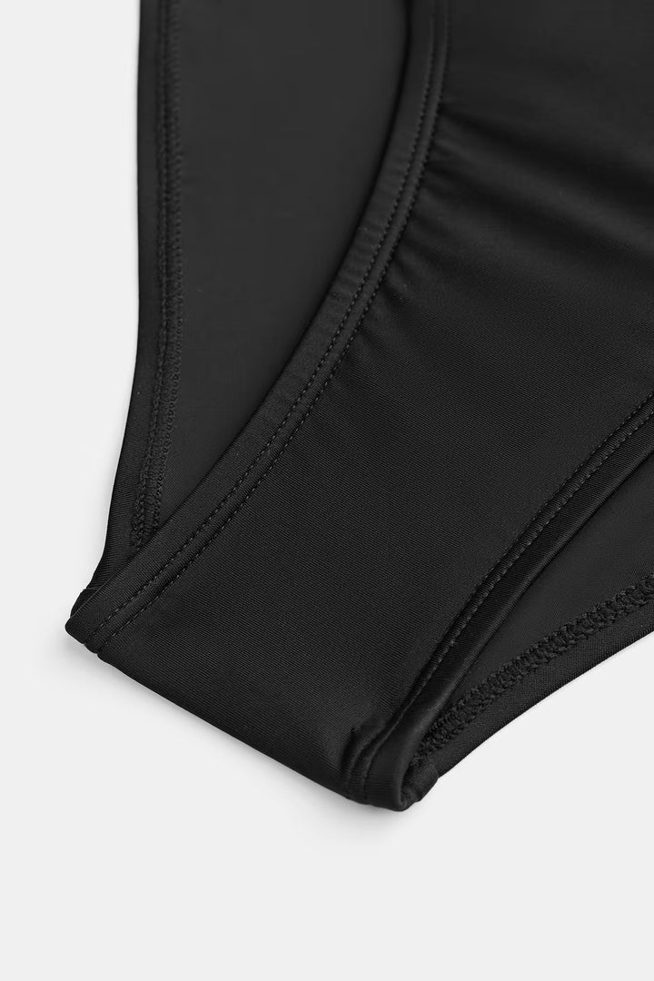 Close up view of the black swimsuit fabric and stitching along the leg opening