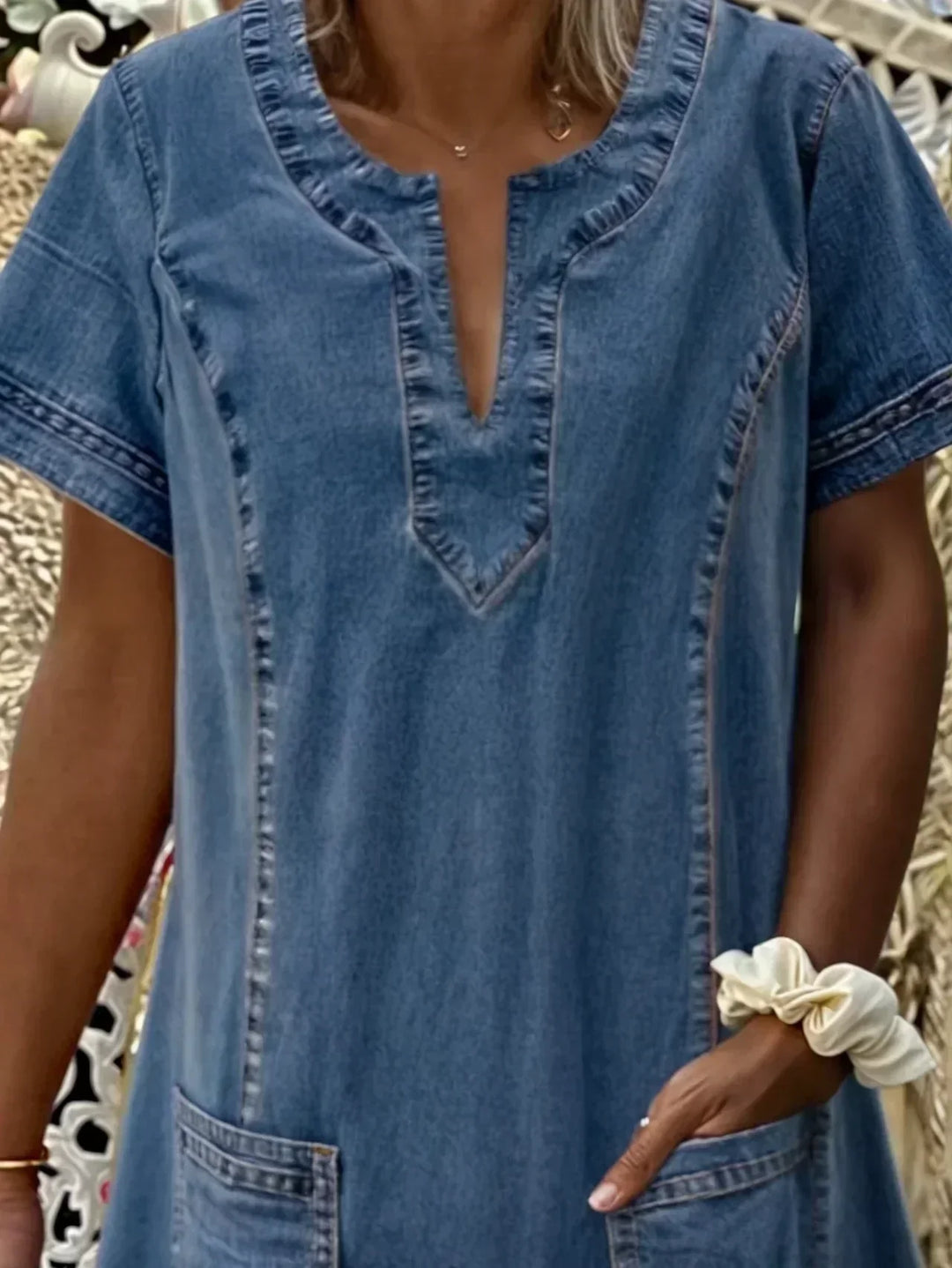 Close up of women blue denim short sleeve dress v-neckline and detailed stitching