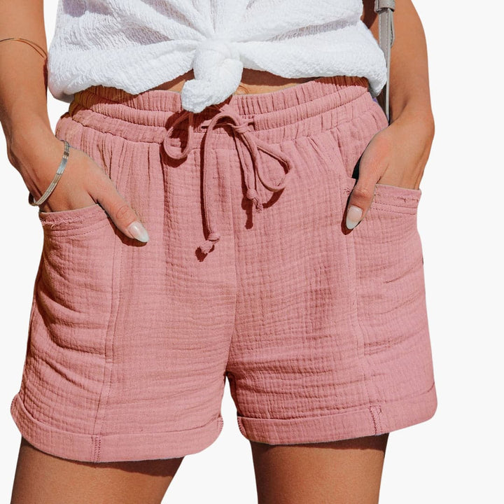 Women pink shorts with a high elastic waist, adjustable drawstring, and front pockets, shown with white top.
