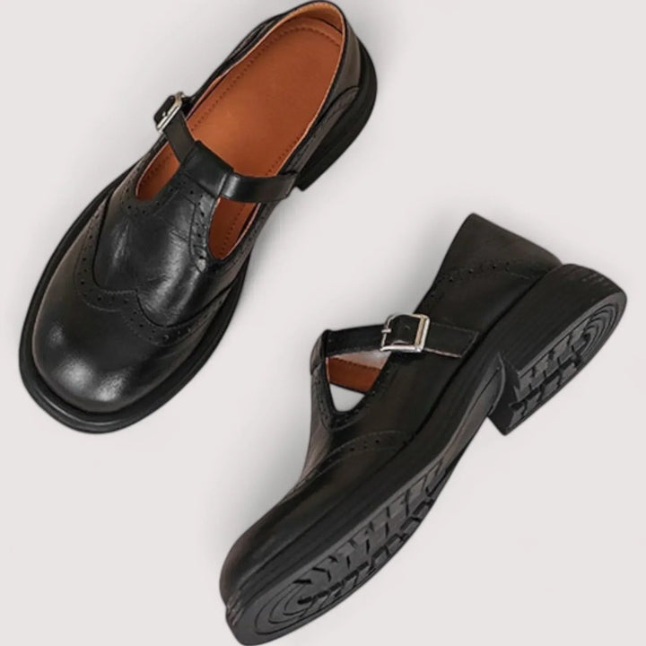 Two black casual buckle Mary Jane shoes with T-strap and brogue details, top view