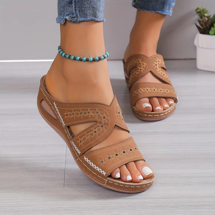 Women brown slip-on sandals with white star-like cut-outs and open toe worn with jeans