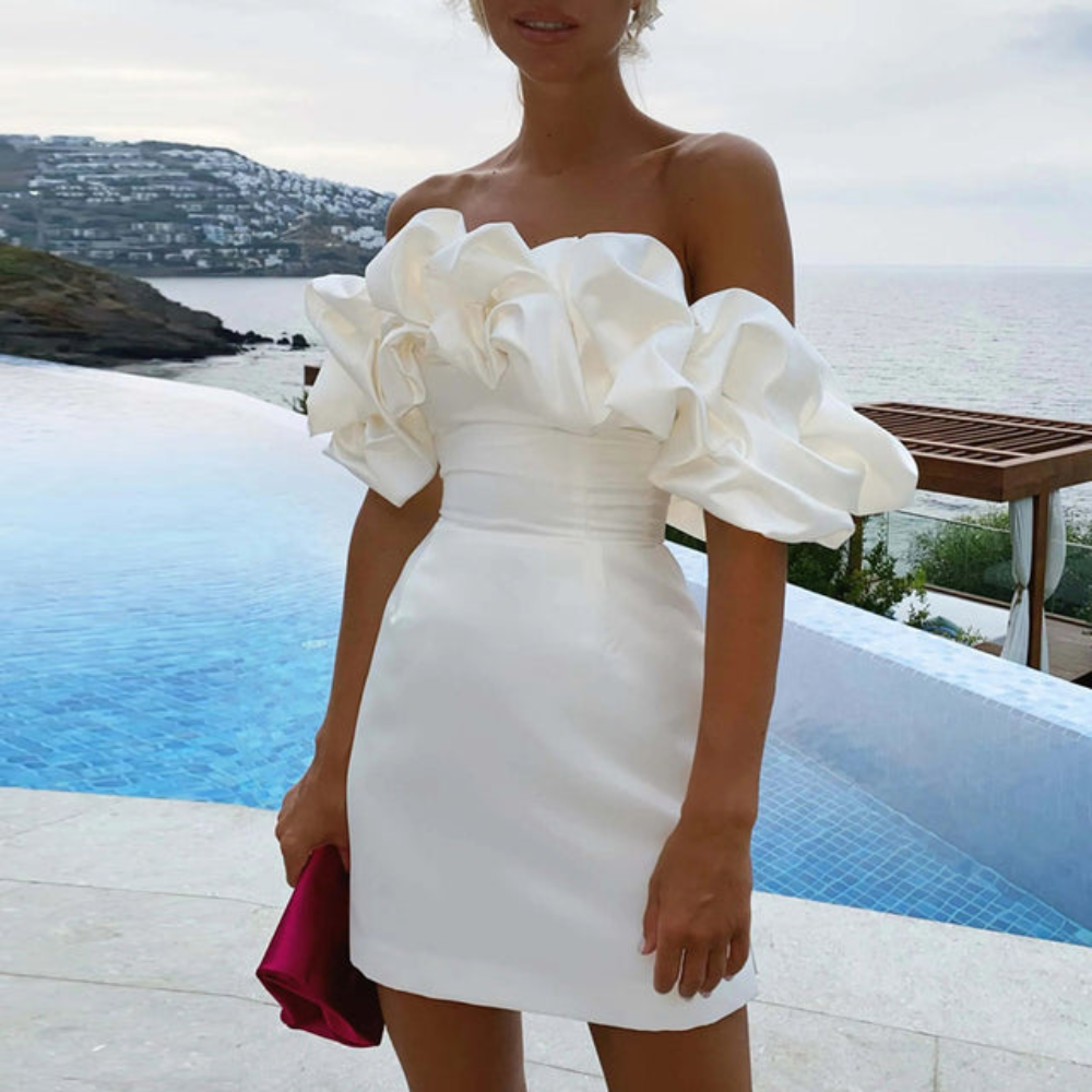 Women white off-shoulder mini dress with ruffled sleeves against a seaside background