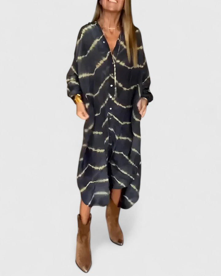Women's patterned maxi dress with loose fit and long sleeves, button placket, model holding sides