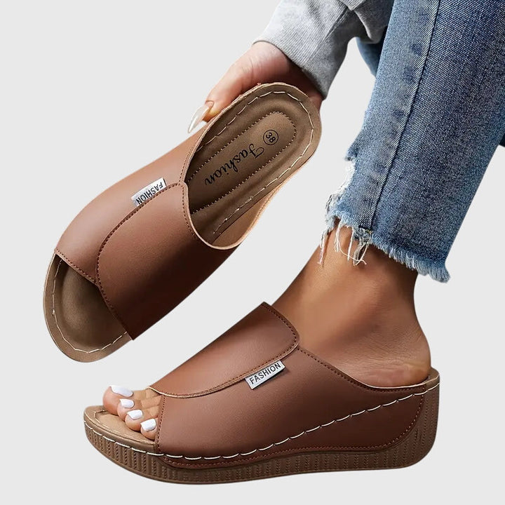 Women brown open toe wedge sandals showing the wide strap and low wedge heel construction.
