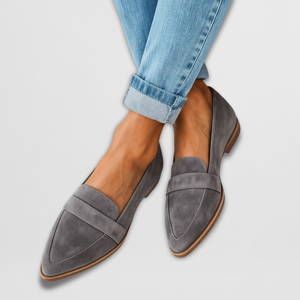Women grey suede pointed toe loafers worn with blue cuffed jeans, showing top view