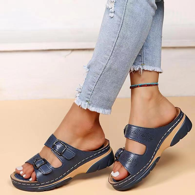 Women's blue laser cut buckle flat sandals on model's feet with ripped jeans