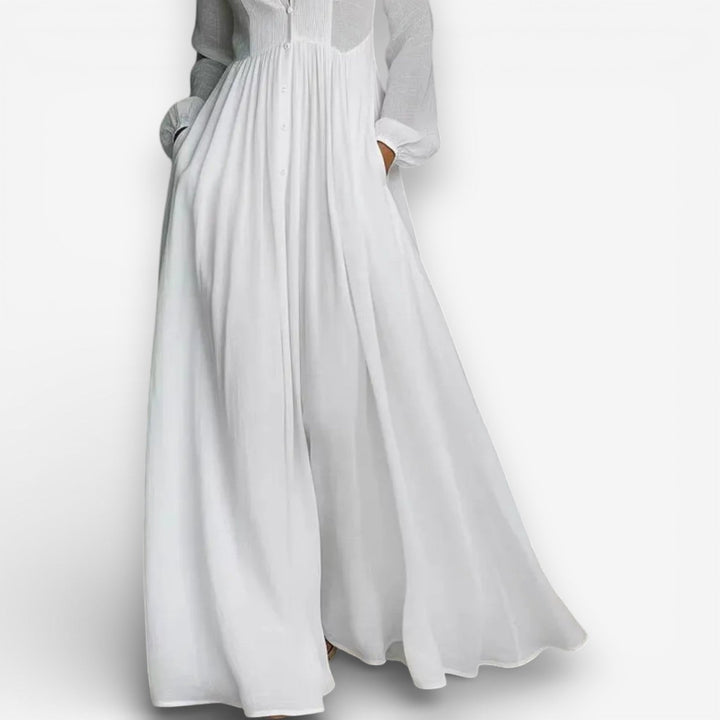 Women white maxi dress showing gathered skirt, side pockets, and long sleeves with cuffs