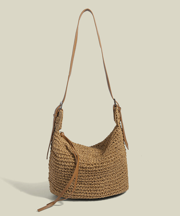 Women tan straw woven bucket bag with brown shoulder strap and tassel detail, front view
