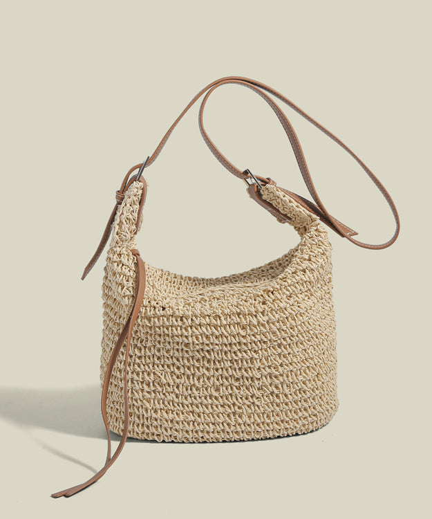 Women light beige straw woven bucket bag with brown adjustable strap, angled view