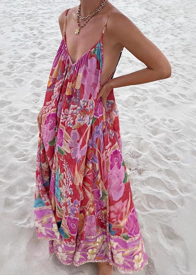 Women's red floral print maxi sundress with spaghetti straps and loose fit seen from side on sand.