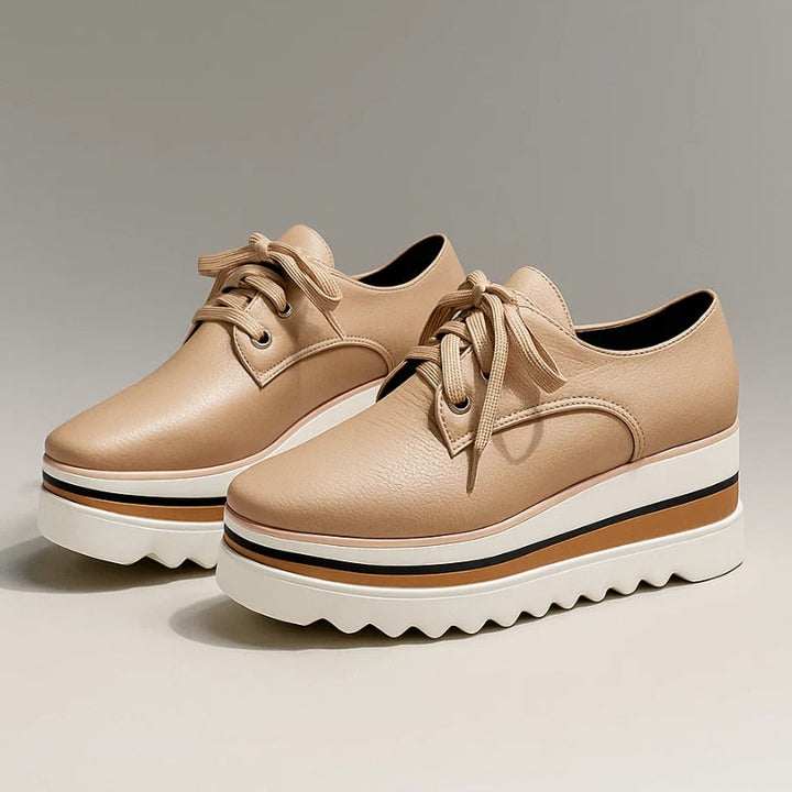 Pair of women beige lace-up platform wedge sneakers with layered soles on a gray background
