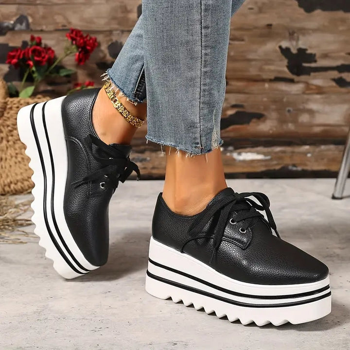 Women black platform wedge sneakers with white striped sole and sawtooth tread pattern with jeans