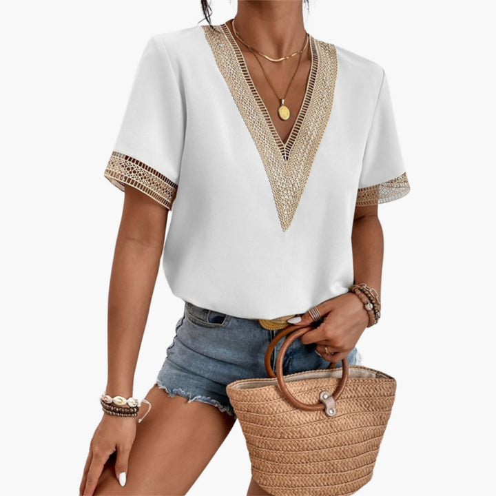Women's white V-neck short sleeve blouse with lace trim detailing on neckline and short sleeves.