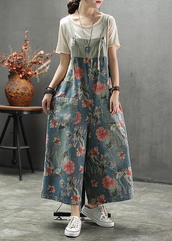 Women's light blue floral printed midi denim romper with front patch pockets and adjustable straps, front view.