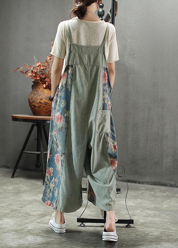 Women's light blue floral printed midi denim romper with adjustable straps, back view.