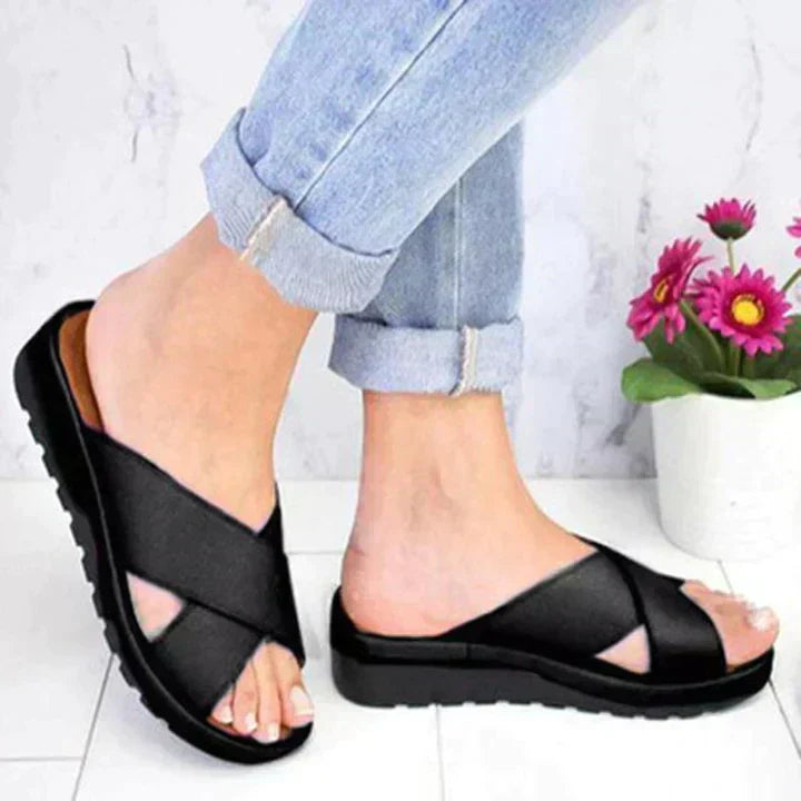Women's black casual platform sandals with crossed straps, worn with jeans