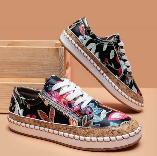 Women black floral print sneakers with white laces and side zipper on a wooden box