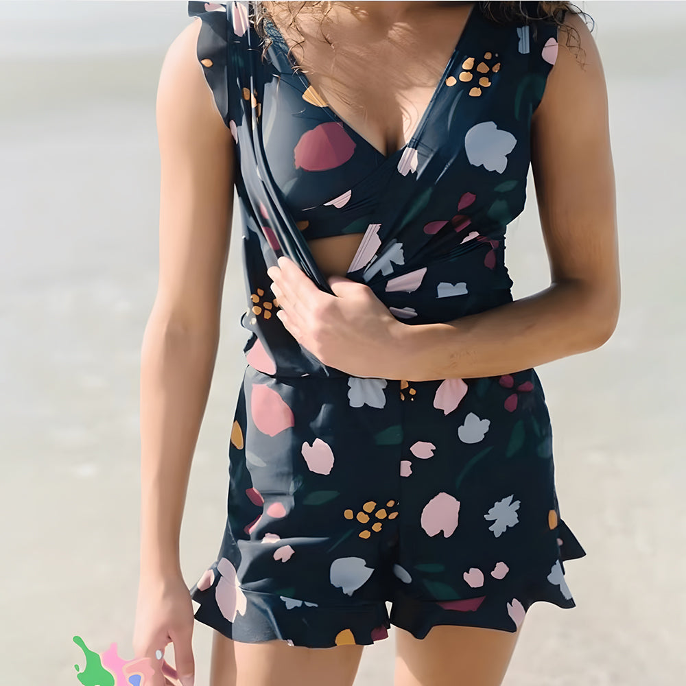 Women navy floral print sleeveless romper with V-neckline and ruffle hem on shorts on a beach