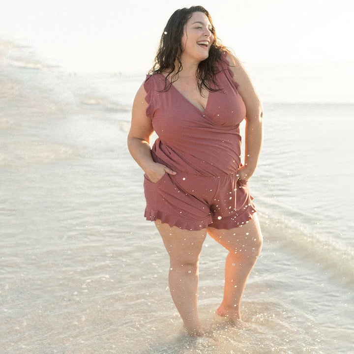 Women berry sleeveless romper with V-neckline standing in shallow water, showing ruffle detail