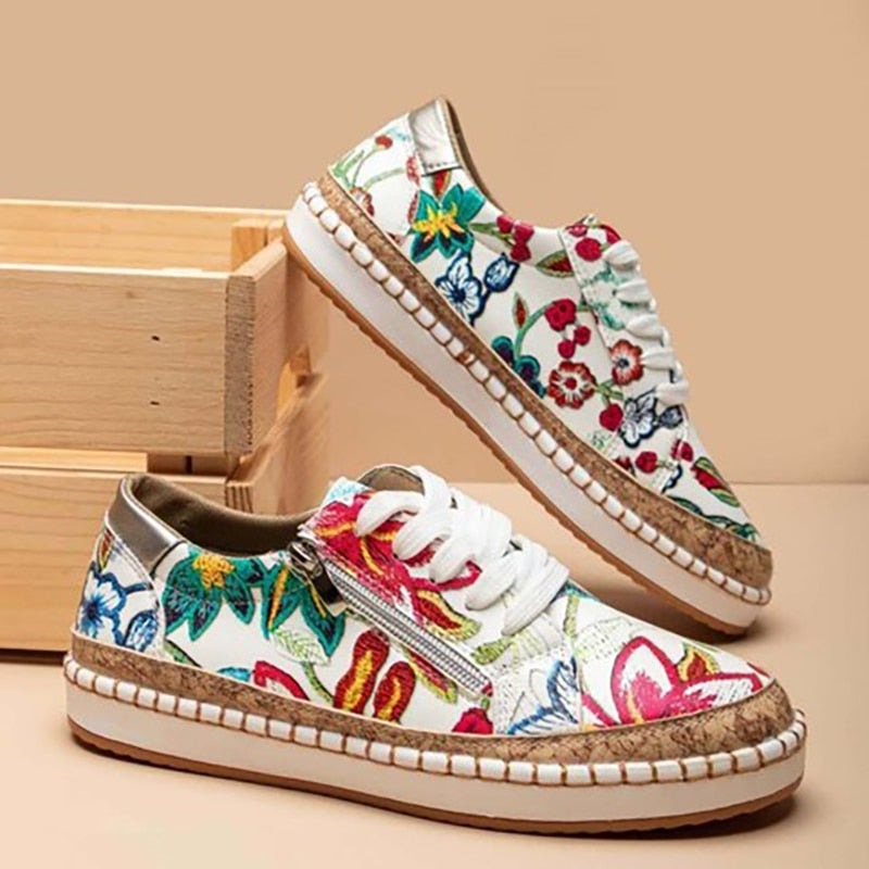 Women white floral print sneakers with white laces and side zipper on a wooden box