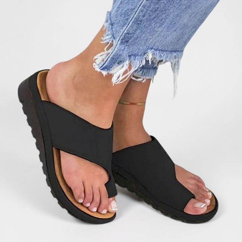 Women's black toe split open toe sandals with ridged sole and wide foot strap, worn with jeans.