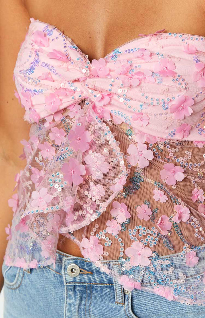 Close up of pink sequin strapless corset top with floral appliques and knotted bust