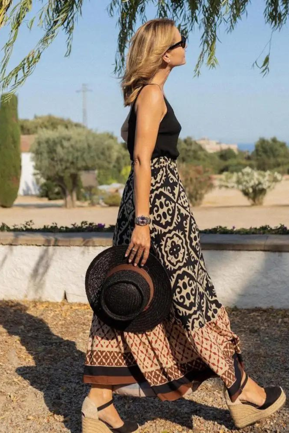 Women black beige printed A line maxi skirt with tiered hem, side profile, outdoor walk