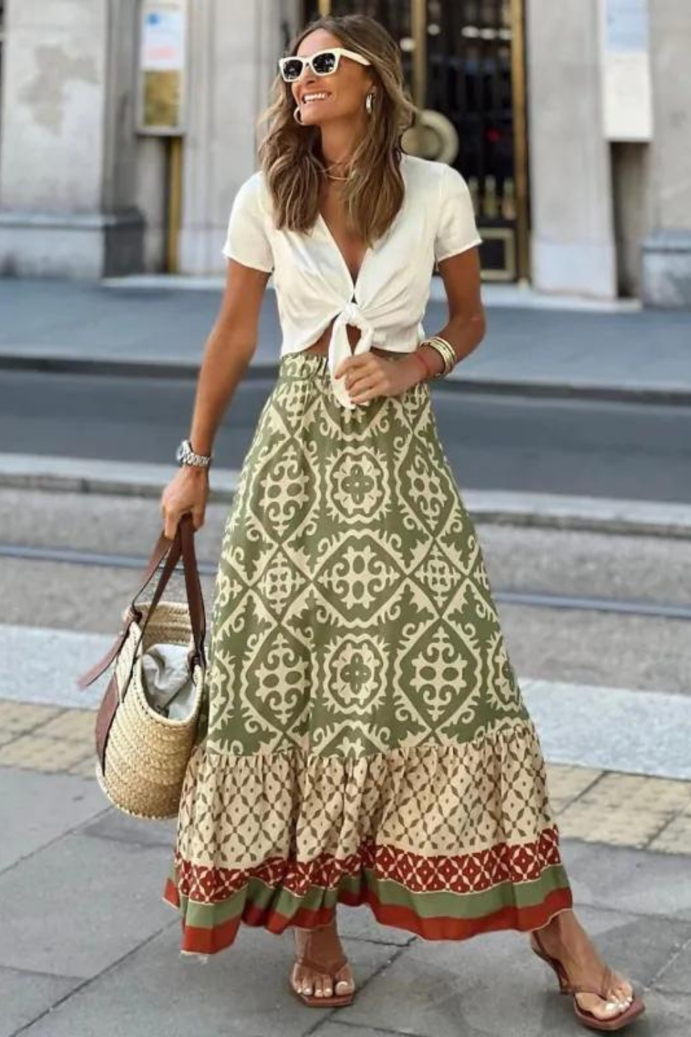 Women olive green printed A line maxi skirt with tiered hem, front view, holding bag