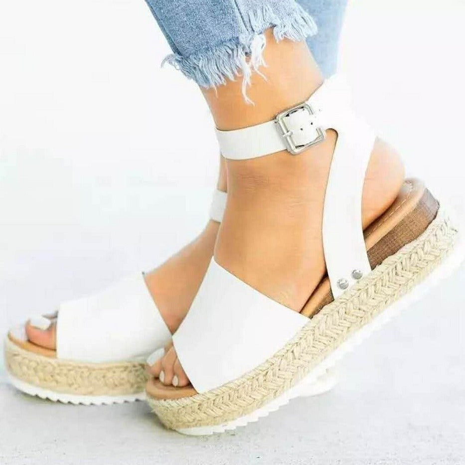 Women white buckle ankle strap flatform sandals with espadrille sole, worn with jeans.