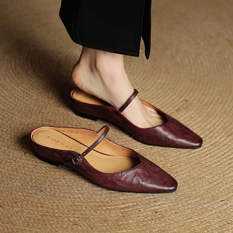 Women burgundy slip-on mules with buckle strap on a woven rug
