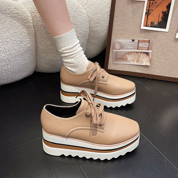 Women beige platform wedge sneakers with multi-color striped sole and sawtooth tread on dark floor